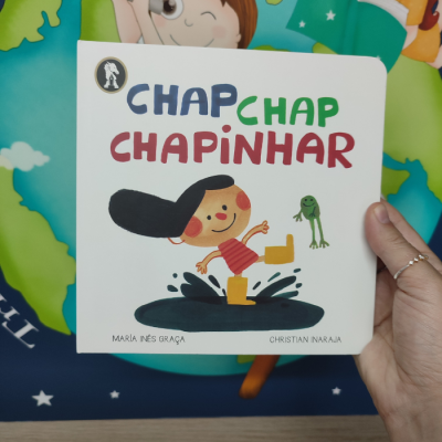 Capa de livro infantil com ilustração de criança a saltar numa poça e sapo