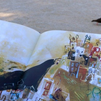 Livro ilustrado aberto no chão com pássaro ao fundo