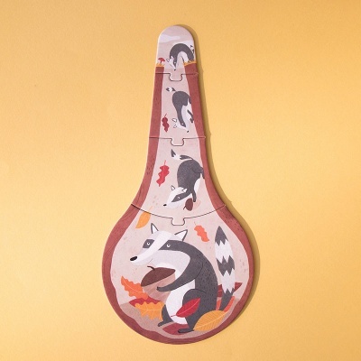 Quebra-cabeças em formato de colher com raposas e folhas em tons naturais, fundo amarelo