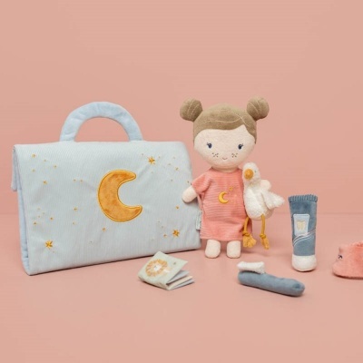 Conjunto de brinquedos com mala azul clara, boneca de pano cor-de-rosa, pato, livro e acessórios sobre fundo rosa.