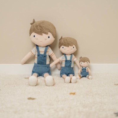 Três bonecos de tecido com roupa azul e castanha sentados no chão claro