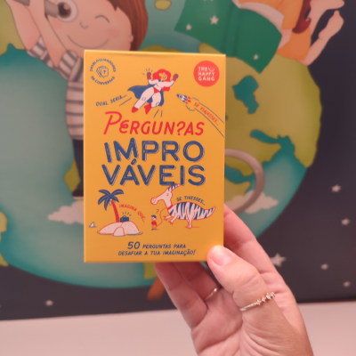 Caixa amarela com texto e ilustrações coloridas segurada por mão com anel