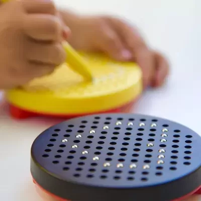 Brinquedos circulares perfurados com bolas metálicas e mão de criança