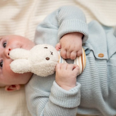 Bebé de malha azul claro a segurar peluche de coelho