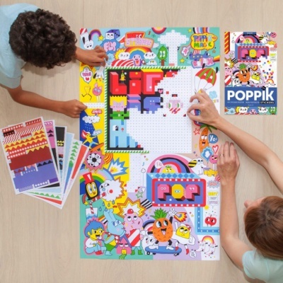 Crianças a montar puzzle autocolante POPPIK com personagens coloridos numa mesa.