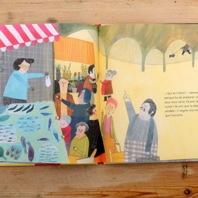 Livro aberto com ilustração de mercado e texto em português.