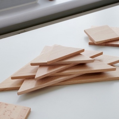 Peças de madeira claras em formas triangulares e quadradas sobre superfície branca