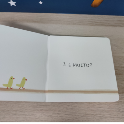 Página aberta de livro infantil com dois pintainhos amarelos e texto '3 É MUITO?'.