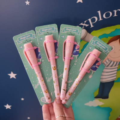 Quatro canetas mágicas rosa embaladas em cartões verdes com fundo azul estrelado e desenho de criança