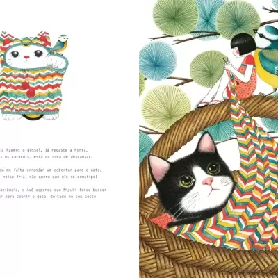 Gato preto e branco numa manta colorida sobre cama de vime com menina e pássaro numa árvore