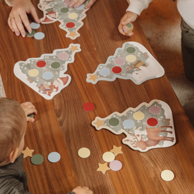 Cartões de árvore de Natal com peças coloridas e crianças a jogar numa mesa de madeira