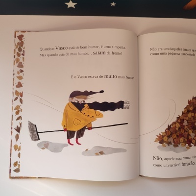 Página de livro infantil com ilustração de personagem com casaco amarelo e cachecol preto