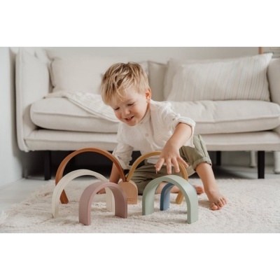 Brinquedo de arcos em madeira colorida sobre tapete claro com criança a brincar