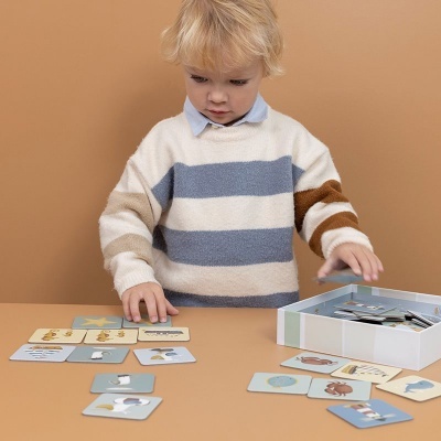 Criança loira a brincar com cartas educativas e caixa aberta sobre mesa clara