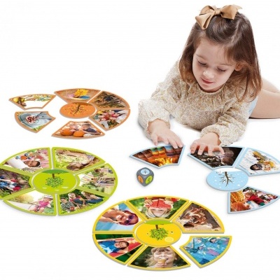Criança a jogar com tabuleiros circulares coloridos com imagens e um dado no chão