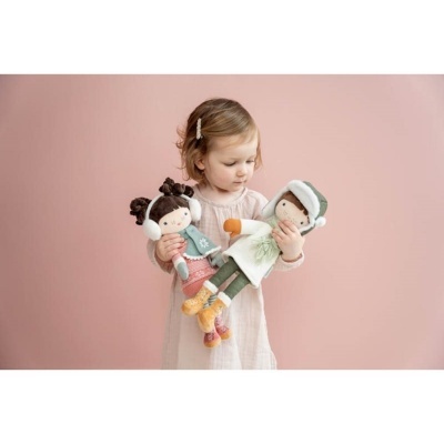 Criança com duas bonecas de pano em fundo rosa claro