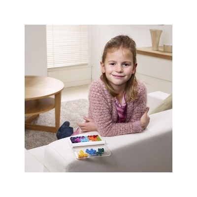Menina num sofá branco com caixa colorida de peças de encaixe numa sala clara