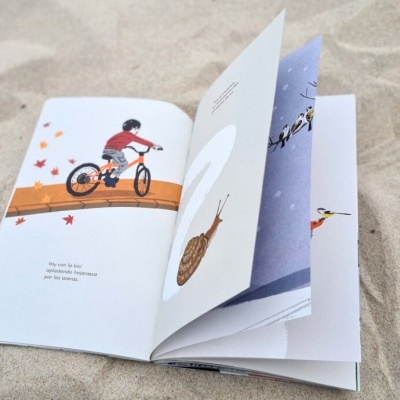 Livro infantil aberto sobre areia com ilustrações coloridas