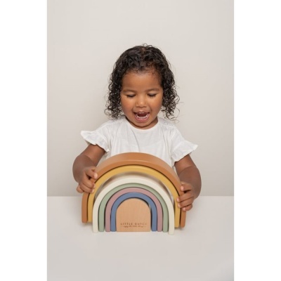 Criança com brinquedo arco-íris de madeira colorida em tons terra