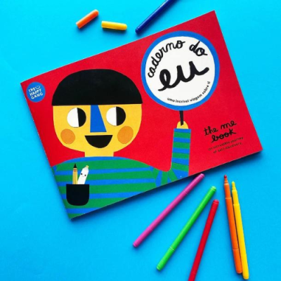 Caderno com capa vermelha e ilustração de pessoa estilizada com canetas coloridas ao redor