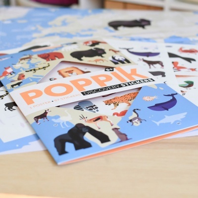 Livro azul de adesivos com desenhos de animais sobre uma mesa de madeira.