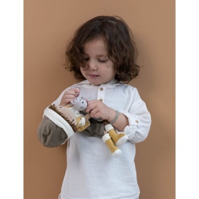 Criança vestindo túnica branca segura boneco de tecido colorido