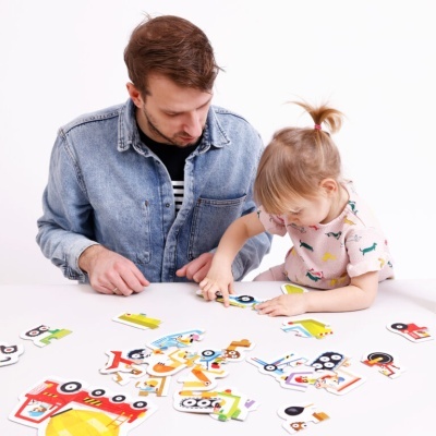 Homem e menina a montar puzzle de madeira colorido com veículos e personagens