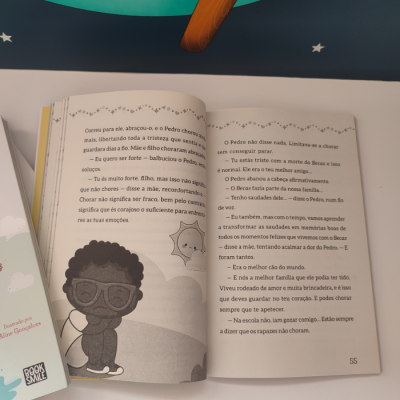 Livro infantil aberto com texto em português e ilustração a preto e branco de uma criança com óculos