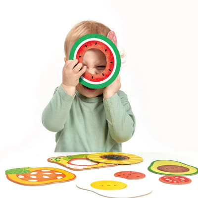 Criança brincando com anéis de brinquedo em forma de frutas coloridas.