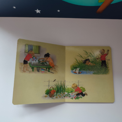Livro infantil aberto com ilustrações de crianças a brincar ao ar livre