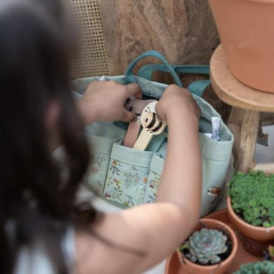 Bolsa verde claro com padrão floral e régua de madeira perto de plantas suculentas em vasos de terracota
