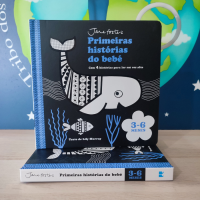 Livro infantil 'Primeiras histórias do bebê' com baleia em preto, branco e azul sobre mesa