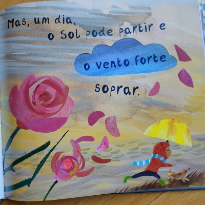 Página de livro ilustrado com texto em português, rosa cor-de-rosa, menino com guarda-chuva amarelo e céu colorido