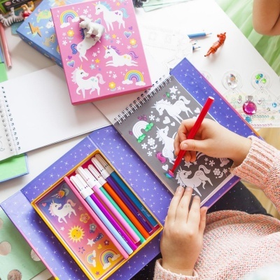 material escolar colorido com tema de unicórnios sobre mesa branca