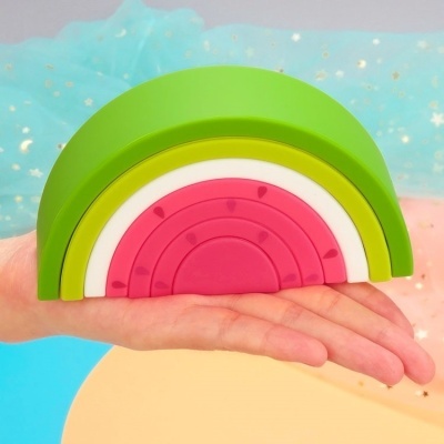 Brinquedo empilhável arco-íris em madeira com cinco peças coloridas sobre a mão de uma pessoa