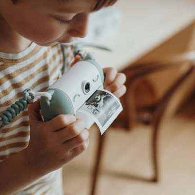 Criança com impressora portátil a imprimir fotografia a preto e branco