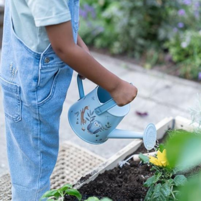 Criança a regar planta com regador azul decorado com pássaros e folhas