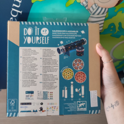 Caixa azul e bege de kit Do It Yourself para montar caleidoscópio com padrões coloridos