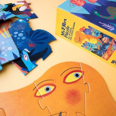 Peças de puzzle coloridas com rosto amarelo e padrões azuis ao lado de caixa amarela com texto e imagens de dinossauros