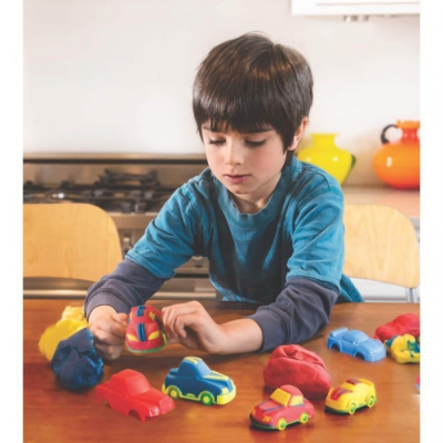 Criança com carros de brinquedo coloridos numa mesa de madeira