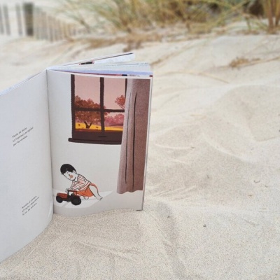 Livro infantil aberto com ilustrações coloridas na areia