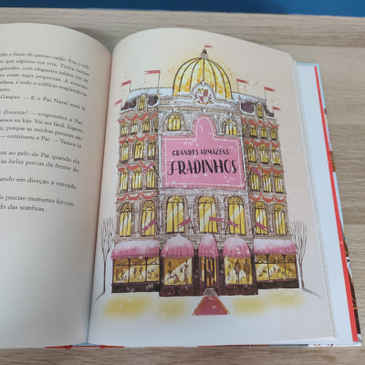 Ilustração de edifício com cúpula e letreiro 'GRANDES ARMAZÉNS FRADINHOS' num livro aberto