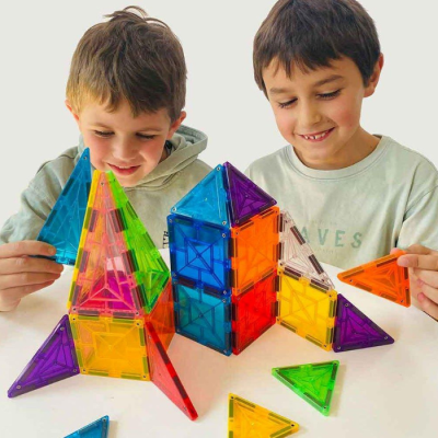 Dois meninos a brincar com blocos magnéticos coloridos em formas geométricas.