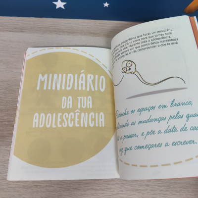Livro aberto com texto e ilustração colorida sobre mesa