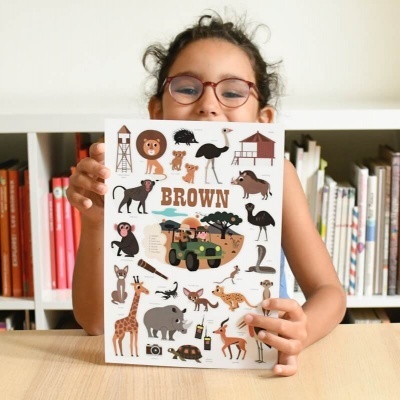 Menina com óculos a segurar livro ilustrado com animais e texto BROWN