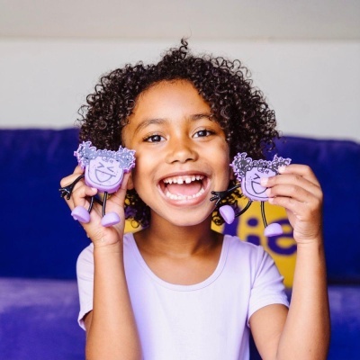 Criança segurando keychains roxos com rosto sorridente no sofá azul