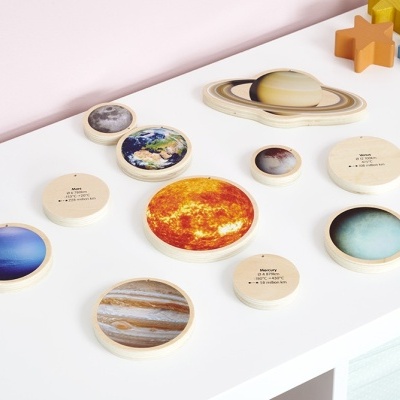 Puzzle de madeira com imagens dos planetas e estrelas coloridas sobre mesa branca