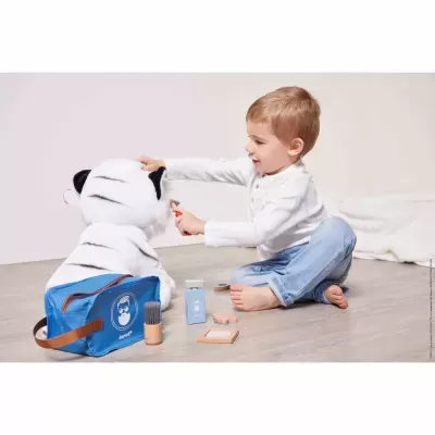 Criança com mochila azul e tigre branco a brincar com acessórios de maquilhagem infantis no chão