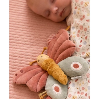 Bebé a dormir com brinquedo de peluche em forma de borboleta num colchão rosa