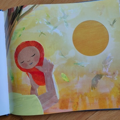 Página de livro infantil com ilustração de boneca com capuz vermelho e sol amarelo